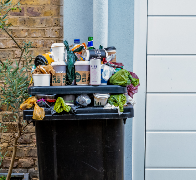 a full wheelie bin with rubbish piled on top
